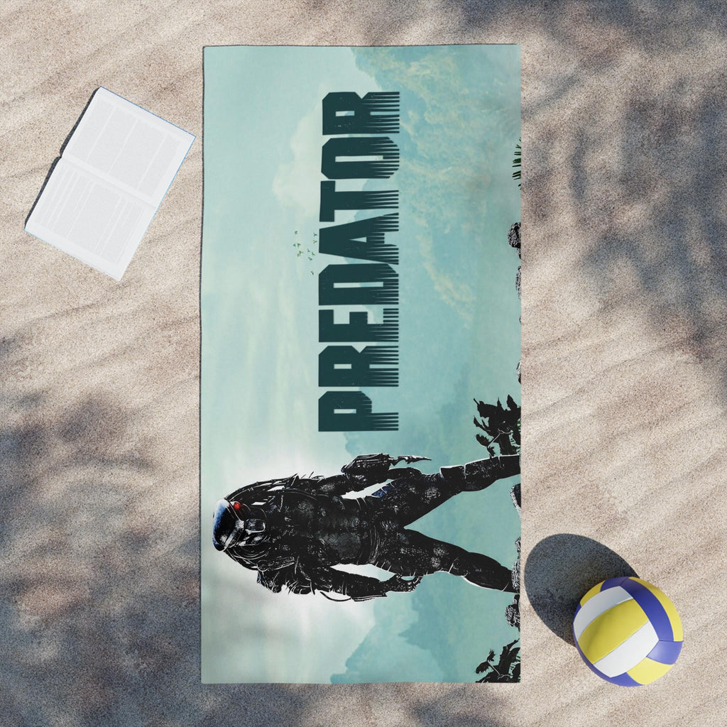 Towel with 'Predator' design on a sandy surface with a volleyball and paper.