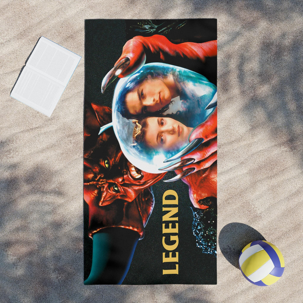 Towel with 'Legend' design featuring two faces and red hands on a sandy background