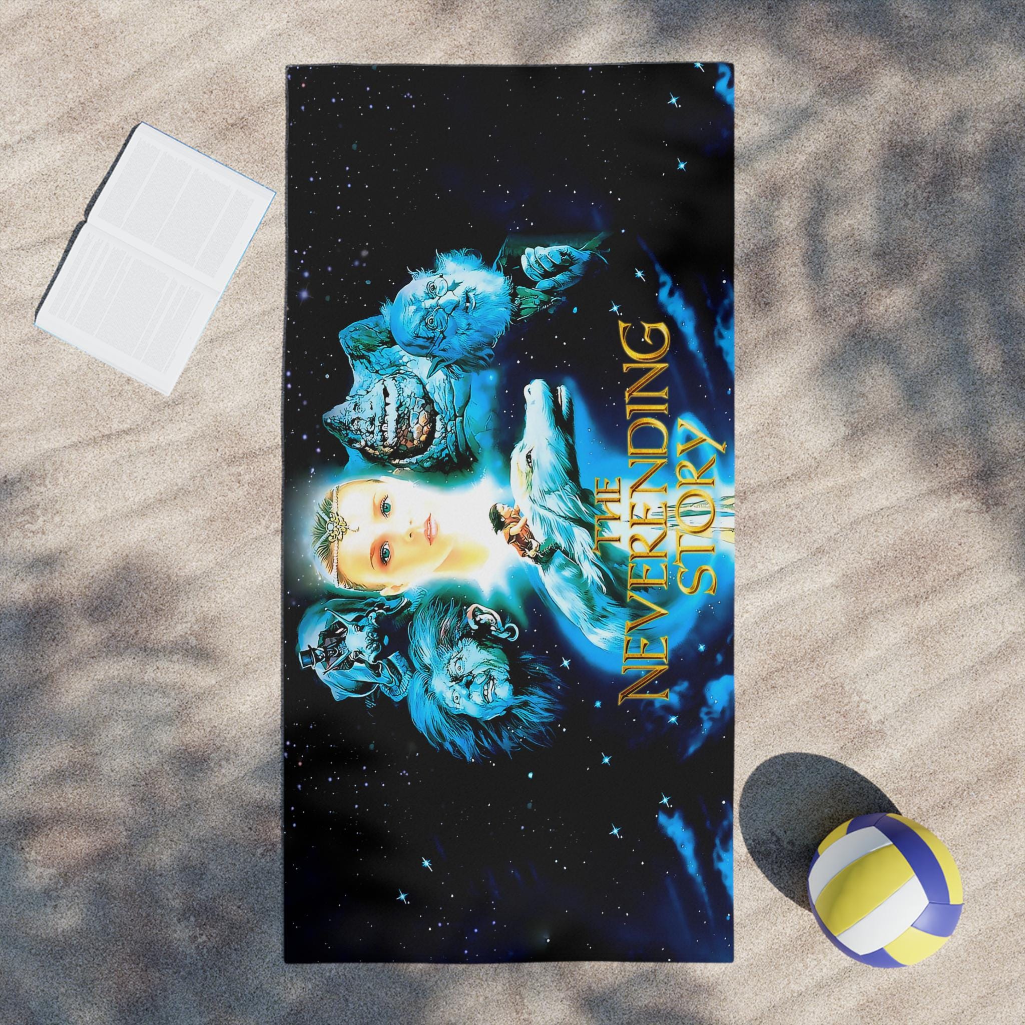 Towel with 'The Neverending Story' design on a sandy surface