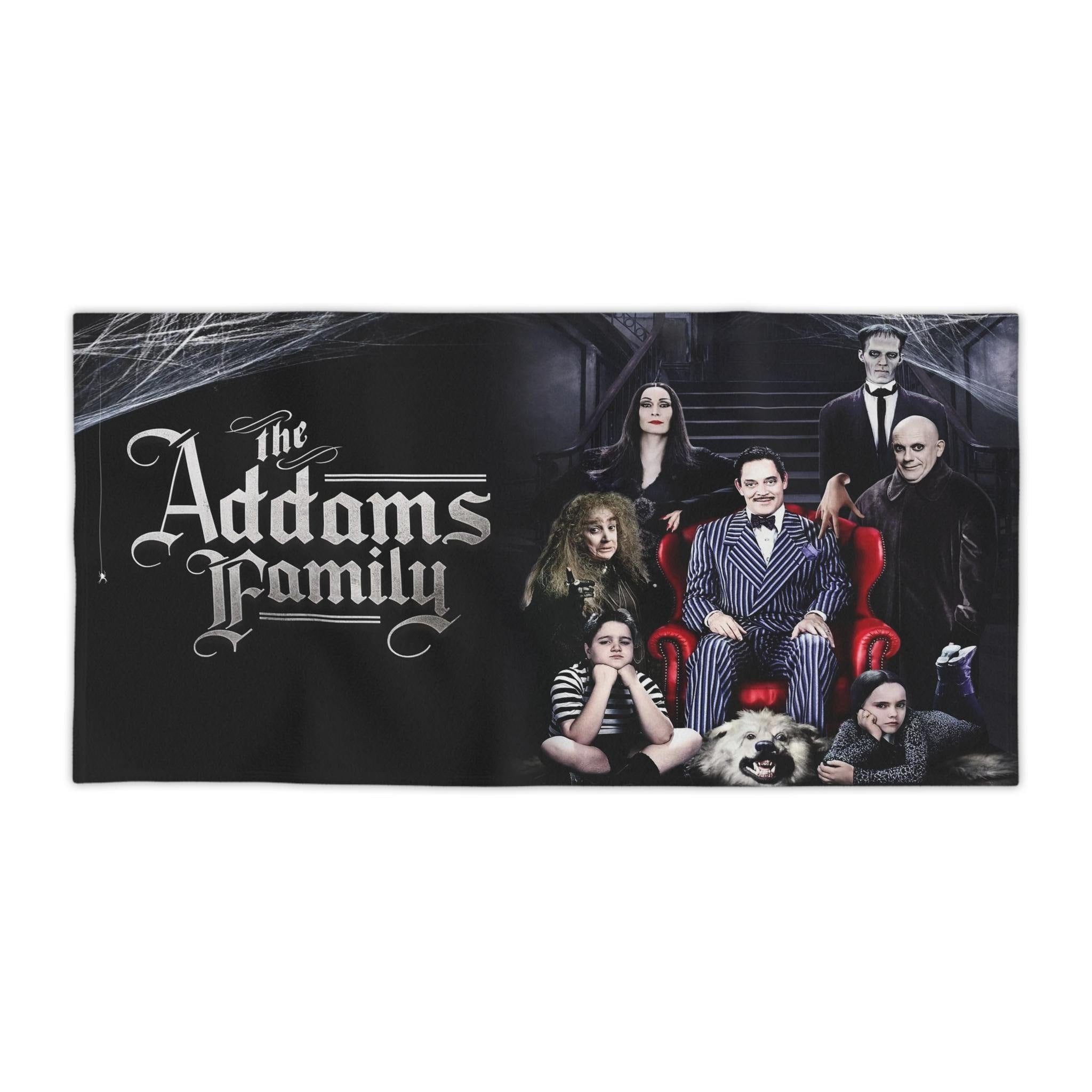 Black beach towel featuring a high-quality print of the full Addams Family cast seated in a gothic mansion setting with the movie logo on the left.
